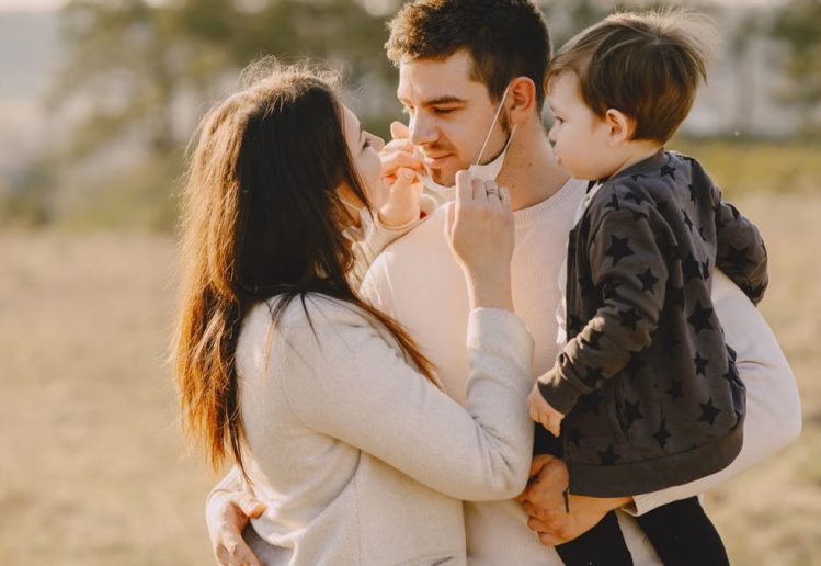 Family sharing affectionate moments outdoors with parents and child enjoying the sunny day.
