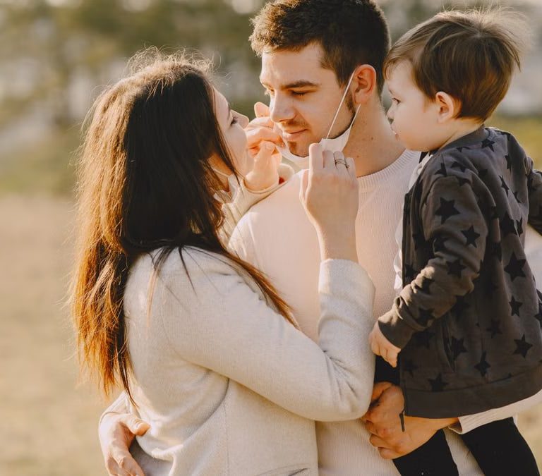 Family sharing affectionate moments outdoors with parents and child enjoying the sunny day.